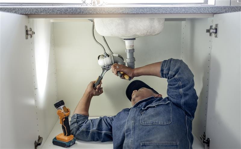 Plumber repairing pipes beneath a bathroom sink in Sun City Center