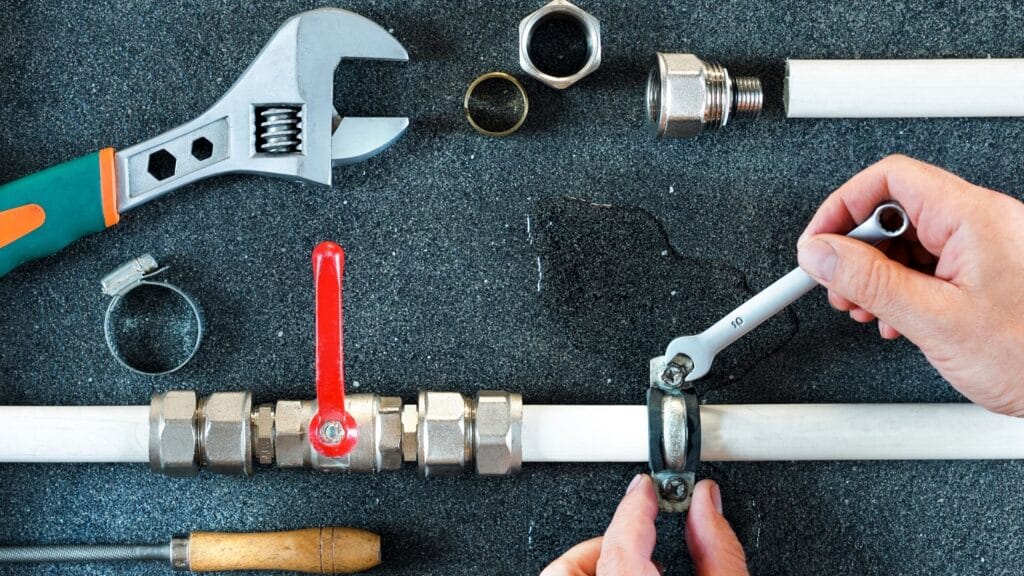 Plumber repairing a pipe valve with an adjustable wrench in Sun City Center