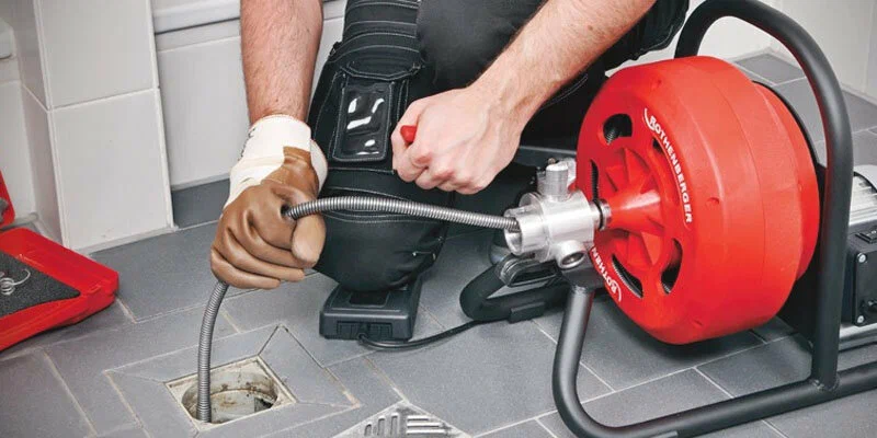 Plumber using a drain-cleaning machine in Sun City Center