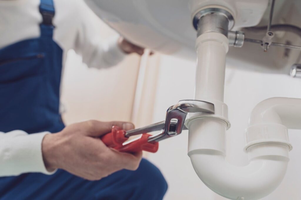 Plumber repairing a white drain pipe beneath a sink in Sun City Center