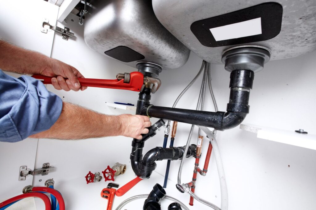 Plumber repairing drain pipes beneath a kitchen sink in Sun City Center