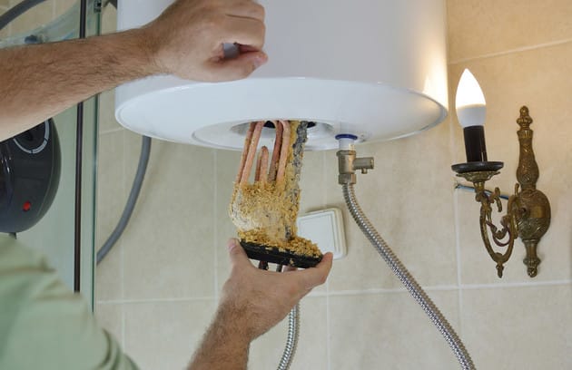 Technician removing mineral buildup from a water heater in Sun City Center
