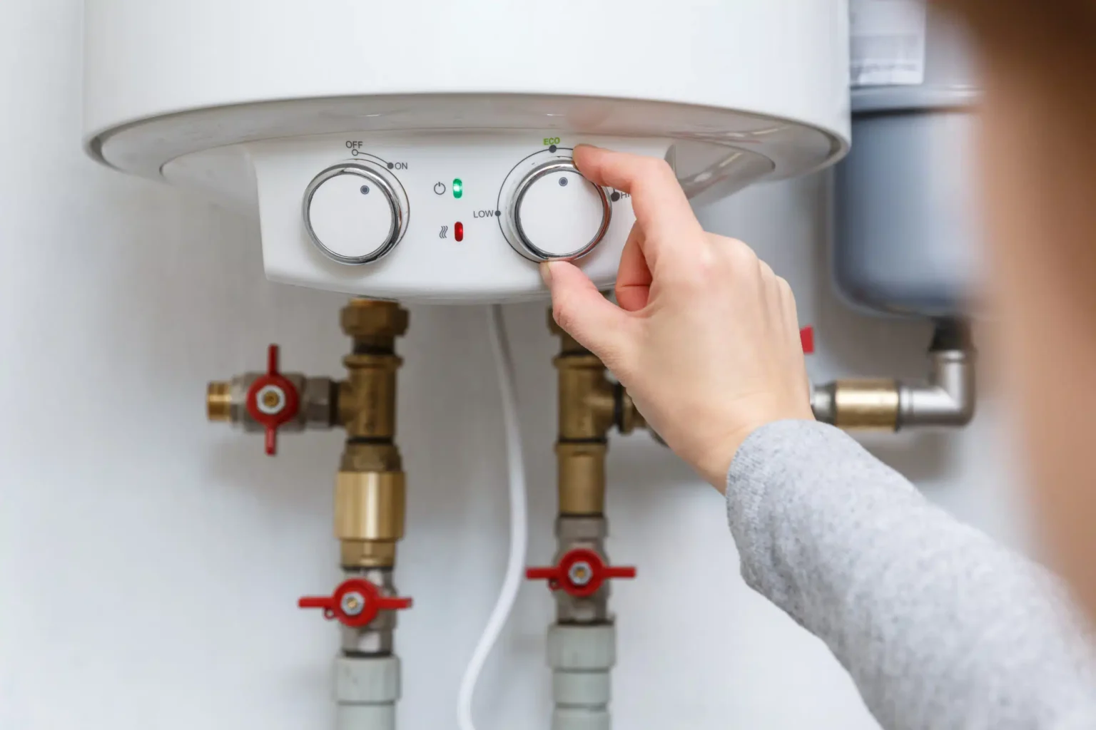 Homeowner adjusting the temperature controls on a water heater in Sun City Center